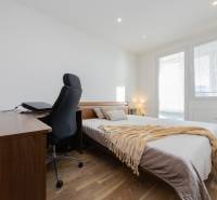 REZERVOVANÝ ZARIADENÝ 4-IZB.  BYT V TOP LOKALITE, DUBNICA NAD VÁHOM - Spálňa v 4-izbovom byte s priestrannou posteľou, stolom a podlahou s dreveným dekorom.