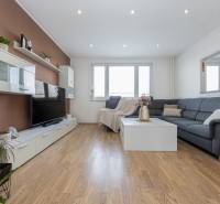 REZERVOVANÝ ZARIADENÝ 4-IZB.  BYT V TOP LOKALITE, DUBNICA NAD VÁHOM - Obývacia izba so sedačkou, televízorom a podlahou s dreveným dekorom v 4-izbovom byte.