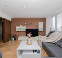 REZERVOVANÝ ZARIADENÝ 4-IZB.  BYT V TOP LOKALITE, DUBNICA NAD VÁHOM - Obývacia izba v 4-izbovom byte s pohovkou, stolom, televíziou a podlahou s dreveným dekorom.