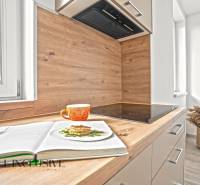 NA PRENÁJOM 3-IZB BYT S BALKÓNOM A ZÁHRADOU,DUN.STREDA - Kuchyňa s podlahou s dreveným dekorom v 3-izbovom byte. V popredí oranžový hrnček.