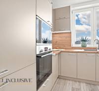 NA PRENÁJOM 3-IZB BYT S BALKÓNOM A ZÁHRADOU,DUN.STREDA - Svetlá kuchyňa s podlahou s dreveným dekorom v 3-izbovom byte, veľké okná a rastliny.