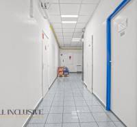 NA PRENÁJOM OBCHODNÝ PRIESTOR V DUNAJSKEJ STREDE - Koridor v obchodných priestoroch s bielymi stenami a dverami lemovanými modrou.