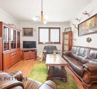 Na predaj 3-izbový rodinný dom, Topoľníky - Obývacia izba v rodinnom dome s koženou sedačkou a podlahou s dreveným dekorom.