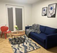 EXKLUZÍVNE-PREDAJ 3-IZBOVÝ BYT POPRAD, širšie centrum 80 m2 s gar.st. - Obývacia izba v 3-izbovom byte s modrou pohovkou, červeným kreslom a podlahou s dreveným dekorom.