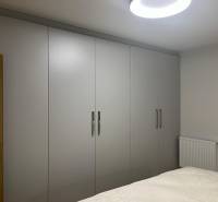 EXKLUZÍVNE-PREDAJ 3-IZBOVÝ BYT POPRAD, širšie centrum 80 m2 s gar.st. - V 3-izbovom byte sú šatníkové skrine s bielymi posuvnými dverami a posteľou.