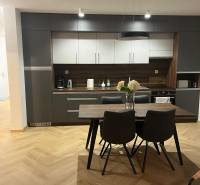 EXKLUZÍVNE-PREDAJ 3-IZBOVÝ BYT POPRAD, širšie centrum 80 m2 s gar.st. - Kuchyňa v 3-izbovom byte so sivými skrinkami a podlahou s dreveným dekorom.