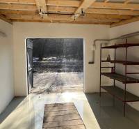 Zrekonštruovaná veľká garáž na ul. Agátova, Dúbravka s pozemkom - Garáže na Agátovej ulici v Bratislave-Dúbravke so železnými policami a otvorenými dverami.