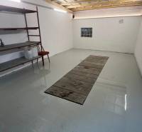 Zrekonštruovaná veľká garáž na ul. Agátova, Dúbravka s pozemkom - Garáže s regálmi a svetlými stenami, podlaha s jamou na opravu vozidiel.