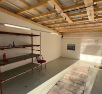 Zrekonštruovaná veľká garáž na ul. Agátova, Dúbravka s pozemkom - Interiér garáže s podlahou s dreveným dekorom a regálom v Bratislave na Agátovej ulici.