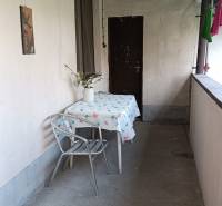 Na predaj RD na bývanie alebo investičná príležitosť Horné Saliby - Zastrešená terasa rodinného domu, stôl so stoličkou, váza s kvetmi, obytný priestor.