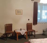 Na predaj RD na bývanie alebo investičná príležitosť Horné Saliby - Izba v rodinnom dome s dreveným stropom, dvomi stoličkami a stolíkom.