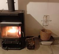 Na predaj RD na bývanie alebo investičná príležitosť Horné Saliby - Krbová pec v rodinnom dome, vedľa ktorej sú košíky s drevom a ovocím.