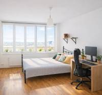 INVESTIČNÉ BÝVANIE V TOP LOKALITE: 2-IZBOVÝ BYT, JÉGÉHO UL, BRATISLAVA - Spálňa v 2-izbovom byte s posteľou, stolom, počítačom a podlahou s dreveným dekorom.