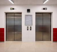 INVESTIČNÉ BÝVANIE V TOP LOKALITE: 2-IZBOVÝ BYT, JÉGÉHO UL, BRATISLAVA - Dva výťahy so sivými dverami a bielymi stenami s červenými obkladmi.