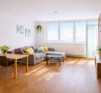 INVESTIČNÉ BÝVANIE V TOP LOKALITE: 2-IZBOVÝ BYT, JÉGÉHO UL, BRATISLAVA - Obývacia izba v 2-izbovom byte s rohovým gaučom a podlahou s dreveným dekorom.