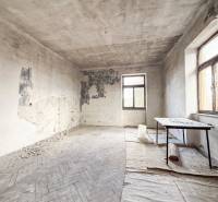 Rodinný dom (bytovka) s pozemkom 554m2, Bobotská Lehota - Opustená miestnosť s poškodenými stenami a podlahou s dreveným dekorom v rodinnom dome.