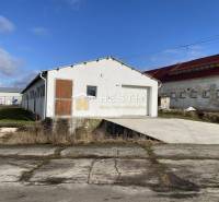 Na prenájom skladová hala, obec Rybky, okr. Senica - Exteriér skladov a hál v Rybkách s bielou fasádou a drevenými dverami.