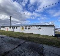 Na prenájom skladová hala, obec Rybky, okr. Senica - Biela budova skladov a hál v Rybkách, obklopená trávou a betónovým chodníkom.