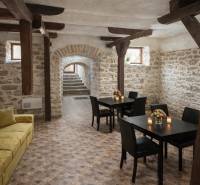 Prenájom gastro priestoru v centre Krupiny - Interiér gastro priestorov s kamennými stenami a podlahou s dreveným dekorom, stoly s kvetmi.