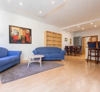 Priestranný 3-izbový byt s loggiou, Staré Mesto - Obývacia izba s modrými sedačkami, farebným obrazom a podlahou s dreveným dekorom v 3-izbovom byte.