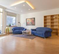 Priestranný 3-izbový byt s loggiou, Staré Mesto - Obývacia izba v 3-izbovom byte s modrými sedačkami a podlahou s dreveným dekorom.