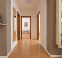 Priestranný 3-izbový byt s loggiou, Staré Mesto - Chodba v 3-izbovom byte s podlahou s dreveným dekorom, zrkadlom a sklenenou vitrínou.