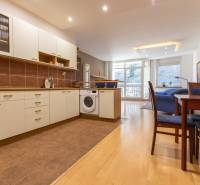 Priestranný 3-izbový byt s loggiou, Staré Mesto - Kuchyňa s podlahou s dreveným dekorom, práčkou a jedálenským stolom v 3-izbovom byte.