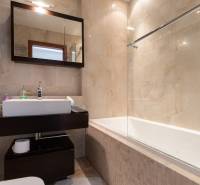 Moderný 2-izbový byt s balkónom, Eurovea - Kúpeľňa s vaňou a tmavým nábytkom v 2-izbovom byte, svetlé obkladačky.