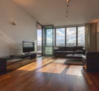 Moderný 2-izbový byt s balkónom, Eurovea - Obývacia izba v 2-izbovom byte s podlahou s dreveným dekorom a veľkými oknami.