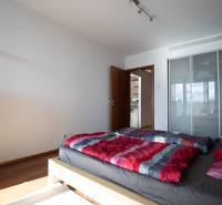 Moderný 2-izbový byt s balkónom, Eurovea - Spálňa v 2-izbovom byte s podlahou s dreveným dekorom, posteľou a skriňou.