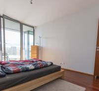 Moderný 2-izbový byt s balkónom, Eurovea - Spálňa v 2-izbovom byte s podlahou s dreveným dekorom a prístupom na balkón.