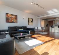 Moderný 2-izbový byt s balkónom, Eurovea - Obývačka v 2-izbovom byte s podlahou s dreveným dekorom a čiernym koženým gaučom.