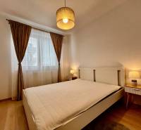 PRENÁJOM NOVOSTAVBA 2 izb.byt, BALKÓN, PARKOVACIE MIESTO, BIELY KOSTOL - Spálňa s veľkou posteľou, závesmi a podlahou s dreveným dekorom v 2-izbovom byte.