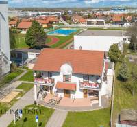 NA PRENÁJOM OBCHODNÝ PRIESTOR-KANCELÁRIA ,DUN. STREDA - Budova s červenou strechou na ulici Jilemnického, obklopená zeleňou a športoviskom, kancelárie.