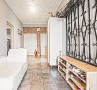 NA PREDAJ VÝNIMOČNÝ RODINNÝ DOM VO VEĽKOM MEDERI - Interiér rodinného domu s bielou pohovkou, stenou s dekorom a botníkom.