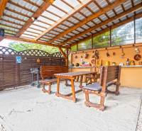 NA PREDAJ VÝNIMOČNÝ RODINNÝ DOM VO VEĽKOM MEDERI - Krytá terasa v rodinnom dome vo Veľkom Mederi s dreveným sedením a dekoráciami.