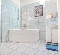 NA PREDAJ VÝNIMOČNÝ RODINNÝ DOM VO VEĽKOM MEDERI - Kúpeľňa v rodinnom dome s rohovou vaňou, umývadlom a obkladmi v modrých odtieňoch.