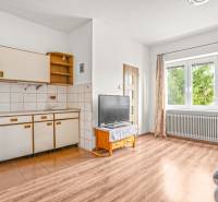 NA PREDAJ VÝNIMOČNÝ RODINNÝ DOM VO VEĽKOM MEDERI - Kuchyňa v rodinnom dome so starším nábytkom, televízorom a podlahou s dreveným dekorom.