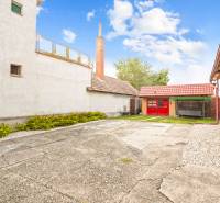 NA PREDAJ VÝNIMOČNÝ RODINNÝ DOM VO VEĽKOM MEDERI - Nádvorie rodinného domu vo Veľkom Mederi s prístavbou a trávnatou plochou.