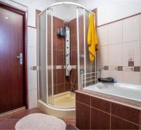 NA PREDAJ 3 IZBOVÝ RODINNÝ DOM, KĽÚČIAROVÉ KRAČANY - Kúpeľňa v rodinnom dome s vaňou, sprchovacím kútom, dverami a žltým uterákom.