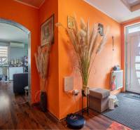 NA PREDAJ 3 IZBOVÝ RODINNÝ DOM, KĽÚČIAROVÉ KRAČANY - Chodba s oranžovými stenami, bielymi dverami a podlahou s dreveným dekorom v rodinnom dome.