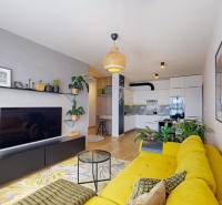 PREDAJ, 3izb. zariadený byt, novostavba Zelená stráň, Košická Nová Ves - Obývačka so žltou sedačkou, nástennými dekoráciami a podlahou s dreveným dekorom v 3-izbovom byte.