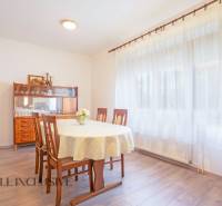ZNÍŽENÁ CENA | NA PREDAJ DVOJGENERAČNÝ RODINNÝ DOM, AMADE KRAČANY - Jedáleň v rodinnom dome, ulica Amade Kračany, drevený nábytok, okno s bielymi závesmi.