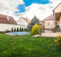 ZNÍŽENÁ CENA | NA PREDAJ DVOJGENERAČNÝ RODINNÝ DOM, AMADE KRAČANY - Rodinný dom na ulici Amade Kračany s bazénom a záhradou, obloha modrá, trávnik upravený.