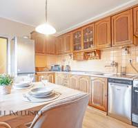 ZNÍŽENÁ CENA | NA PREDAJ DVOJGENERAČNÝ RODINNÝ DOM, AMADE KRAČANY - Kuchyňa s jedálenským stolom, drevenými skrinkami a spotrebičmi v rodinnom dome na ulici Amade Kračany.