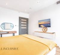 NA PREDAJ NADŠTANDARDNÁ 4-IZB. NOVOSTAVBA, DUN. KLÁTOV - Svetlá spálňa v rodinnom dome s televízorom, zrkadlom a žltou prikrývkou na posteli.