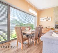 NA PREDAJ NADŠTANDARDNÁ 4-IZB. NOVOSTAVBA, DUN. KLÁTOV - Jedálenský kút v rodinnom dome s dreveným stolom, kreslami a zatemneným oknom.