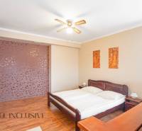 NA PREDAJ PENZIÓN VO VEĽKOM MEDERI – SUNGARDEN - Spálňa s drevenou posteľou, ventilátorom a dekoračnými obrazmi v hoteloch a penziónoch.