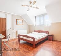 NA PREDAJ PENZIÓN VO VEĽKOM MEDERI – SUNGARDEN - Spálňa v hoteloch a penziónoch s drevenou posteľou, bielym obliečkami a stolom s riadom.