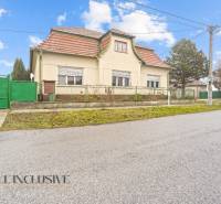 REZERVOVANÉ 4-IZBOVÝ RODINNÝ DOM, TOPOĽNÍKY - Rodinný dom v Topoľníkoch s červenou strechou a zelenou bránou pri ceste.